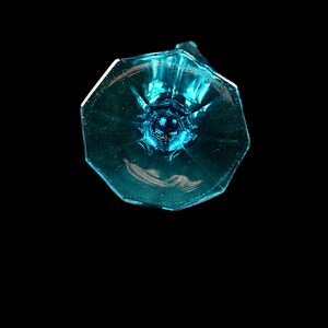 Pode incluir: A base de uma ta&ccedil;a de vidro azul claro com um design facetado.