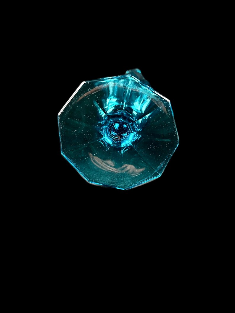 Pode incluir: A base de uma ta&ccedil;a de vidro azul claro com um design facetado.