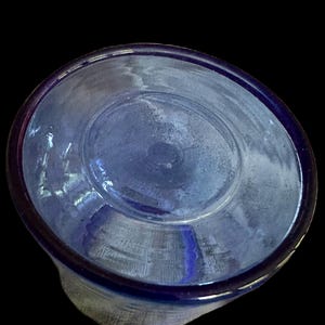 Peut inclure: Gros plan d'un objet en verre bleu, possiblement un verre ou un bol, sur fond noir. Le bord est d'une nuance de bleu plus fonc&eacute;e, et l'int&eacute;rieur a un aspect l&eacute;g&egrave;rement givr&eacute;.