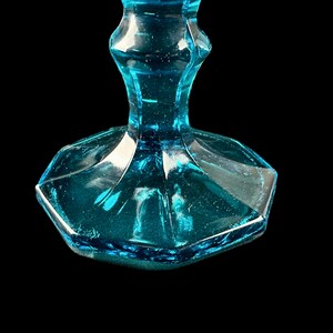 Pode incluir: Close-up da base de um copo de vidro azul turquesa. A base &eacute; octogonal e tem um acabamento ligeiramente fosco.