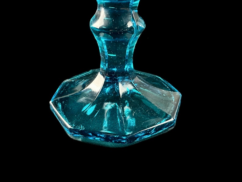 Pode incluir: Close-up da base de um copo de vidro azul turquesa. A base &eacute; octogonal e tem um acabamento ligeiramente fosco.