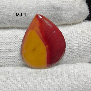 May include: A teardrop-shaped cabochon gemstone with red and yellow colors. The stone has a smooth, polished surface. MJ-1 is written on the white background.