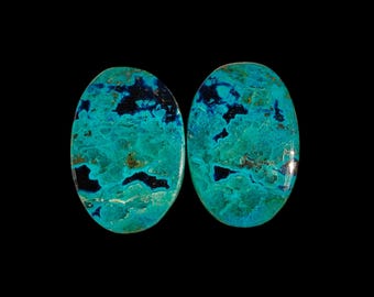 Könnte beinhalten: Zwei ovale türkisfarbene Cabochons mit einem blauen und grünen Marmormuster. Die Cabochons sind poliert und haben eine glatte, glänzende Oberfläche.
