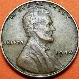 May include: A close-up of a 1944 Lincoln penny. The coin features a profile of Abraham Lincoln, with the words "IN GOD WE TRUST" and "LIBERTY" visible. The year "1944" is also displayed.