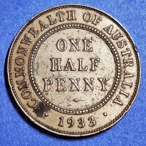 May include: A silver-colored Australian One Half Penny coin from 1933. The coin features the text "COMMONWEALTH OF AUSTRALIA" around the outer edge, with "ONE HALF PENNY" in the center. The year "1933" is at the bottom.