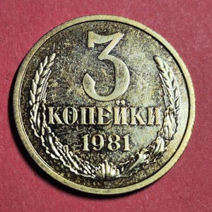 May include: A bronze-colored coin with the number 3 at the top. The text "KOПЕЙКИ" and the year "1981" are visible. The coin is encircled by a wheat wreath.