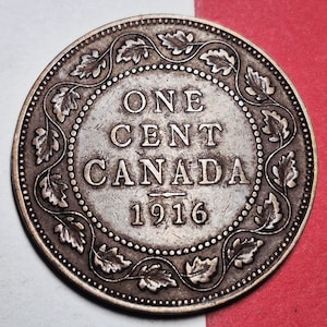 May include: A close-up of a Canadian one-cent coin from 1916. The coin is silver-coloured with the words "ONE CENT CANADA" and the year "1916" in the centre. The coin's edge features a decorative pattern of leaves and dots.