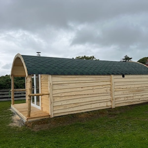 Puede incluir: Una caba&ntilde;a de madera con un techo verde y un peque&ntilde;o porche. La caba&ntilde;a est&aacute; hecha de madera natural y tiene un aspecto r&uacute;stico.