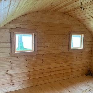 Puede incluir: El interior de una caba&ntilde;a de madera con un techo abovedado y dos ventanas. Las paredes y el suelo son de madera.