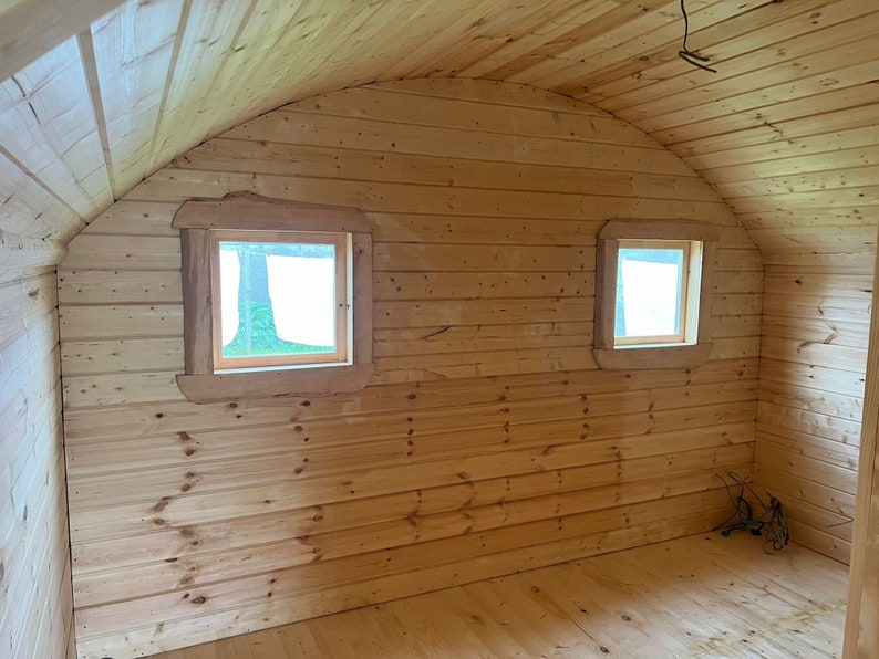 Puede incluir: El interior de una caba&ntilde;a de madera con un techo abovedado y dos ventanas. Las paredes y el suelo son de madera.