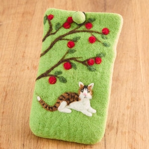 Puede incluir: Una funda de teléfono de fieltro verde con un gato y un árbol con manzanas rojas bordadas.