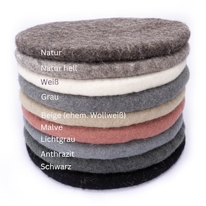 May include: A stack of ten round felt coasters in various shades of grey, brown, beige, and pink. The coasters are labelled with their colour names in German: Natur, Natur hell, Weiß, Grau, Beige (ehem. Wollweiß), Malve, Lichtgrau, Anthrazit, and Schwarz.