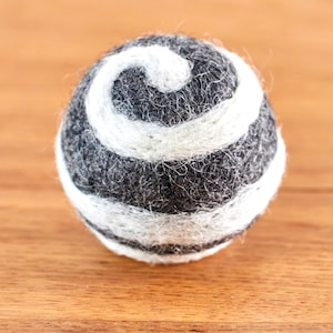 Può includere: Una palla di feltro grigia e bianca con un motivo a spirale bianco.
