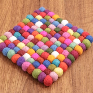 Könnte beinhalten: Ein bunter Filzuntersetzer aus vielen kleinen Kugeln, perfekt zum Schutz von Oberflächen vor heißen Speisen.