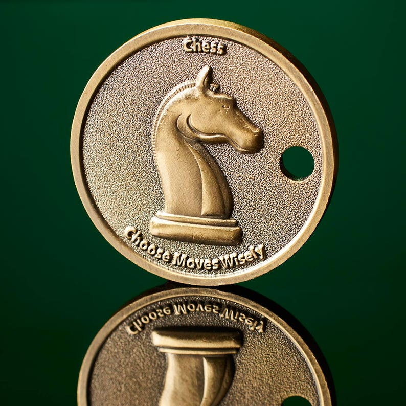 May include: A gold-coloured metal coin with a knight chess piece on one side and the words "Chess Choose Moves Wisely" on the other side.