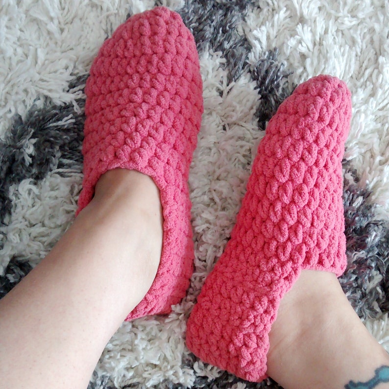 May include: A pair of pink crocheted slippers. The slippers are made with a soft, fuzzy yarn and have a simple, comfortable design.