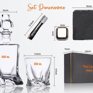 May include: A black gift box with gold trim, a clear glass decanter with a stopper, a clear glass tumbler, a pair of silver tongs, and a black slate coaster. The box has the text "Your Logo Here" printed on it. The decanter holds 840 ml and the tumbler holds 300 ml.