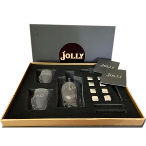 May include: A black gift box with a gold trim, containing a clear glass bottle with the word "JOLLY" etched on it, two clear glasses with the same etching, and a set of silver ice cubes. The box also includes two black coasters with the word "JOLLY" printed on them.