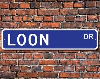 May include: A blue street sign with white lettering that reads "LOON DR."