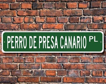 May include: A green and white street sign with the text "PERRO DE PRESA CANARIO PL."