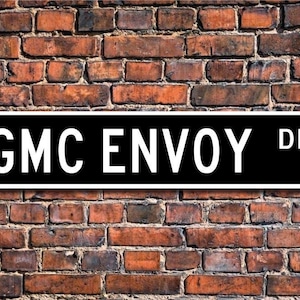 Puede incluir: Señal de calle en blanco y negro con el texto "GMC Envoy Dr."