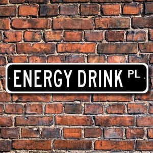a sign that says "Energy Drink PL" against a brick wall background.