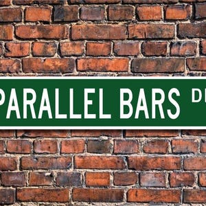 May include: Green street sign with white lettering that reads "PARALLEL BARS DR."
