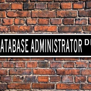 May include: Black and white sign with the text "DATABASE ADMINISTRATOR DR." on a brick wall background.