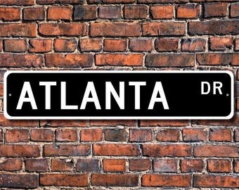 Könnte beinhalten: Schwarz-weißes Straßenschild mit weißem Text, der "ATLANTA DR." lautet.