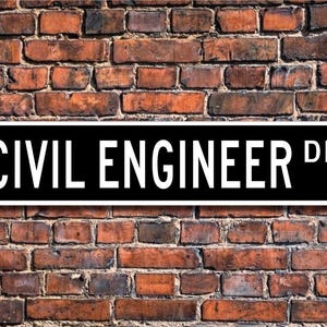 May include: Black and white street sign with the text "CIVIL ENGINEER DR." on a brick wall background.