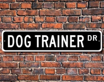 May include: Black and white street sign with the text "DOG TRAINER DR." in white letters.