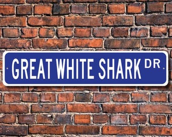 May include: A blue and white street sign with the text "GREAT WHITE SHARK DR." on a brick wall background.