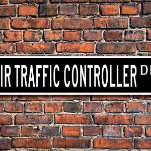 May include: Black and white street sign with the text "AIR TRAFFIC CONTROLLER DR."