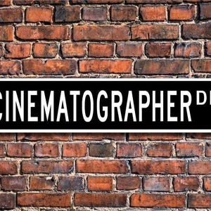 May include: Black and white street sign with the text "CINEMATOGRAPHER DR."