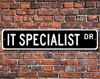 Op de afbeelding: Een zwart-wit straatnaambord met de tekst "IT SPECIALIST DR." op een achtergrond van een bakstenen muur.