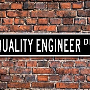 May include: Black and white street sign with the text "QUALITY ENGINEER DR."