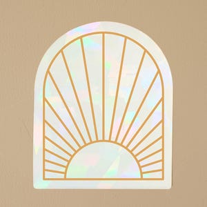 May include: A white iridescent sticker with a gold outline of a sun with rays. The sticker is shaped like an arch.