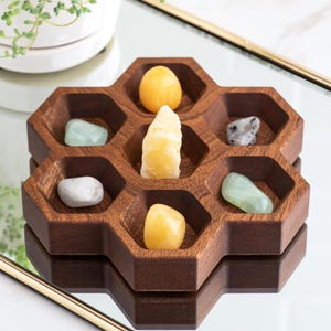May include: A wooden hexagonal tray with six compartments, each containing a different crystal. The crystals are yellow, green, and gray.