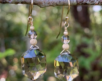 May include: A pair of gold earrings with a faceted smoky quartz gemstone and gold beads hanging from the bottom.
