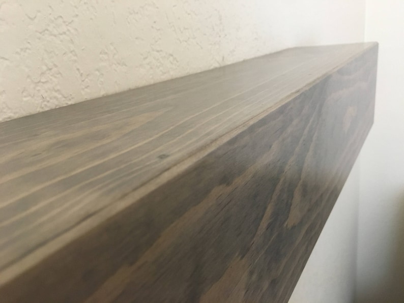 Puede incluir: Un estante flotante rectangular hecho de madera de color marr&oacute;n oscuro con un patr&oacute;n de veta visible. El estante tiene una superficie superior plana y lisa y un borde frontal recto, mostrando la textura natural y los tonos marrones.