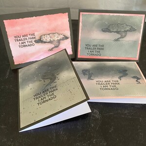 May include: Four greeting cards with a humorous message about a tornado and a trailer park. The cards have a watercolor background and a black border.