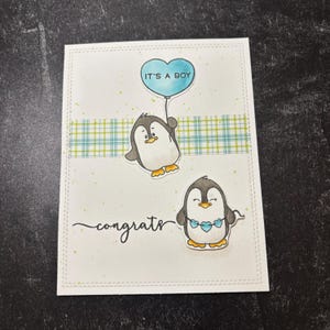 Tarjeta de felicitación hecha a mano con el mensaje "Es un bebé" de Congrats Penguin