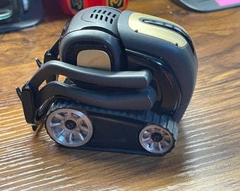 May include: A black and gold toy robot with a track system and a front loader. The robot has a black body with gold accents and a black track system. The front loader is black and has a silver handle.