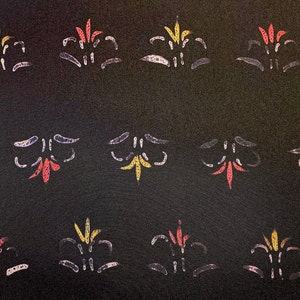 May include: A black background with a repeating pattern of stylized floral designs. The flowers are outlined in white and filled with shades of red, yellow, and orange.
