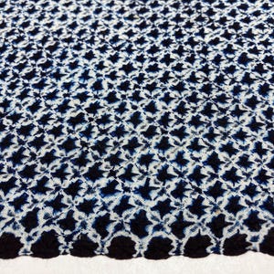 May include: A white fabric with a repeating pattern of dark blue stars. The fabric has a scalloped edge.