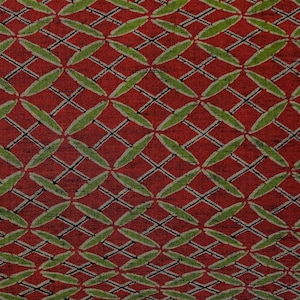 Puede incluir: Tela roja con un patrón geométrico verde y negro. El patrón está formado por círculos y líneas superpuestos.