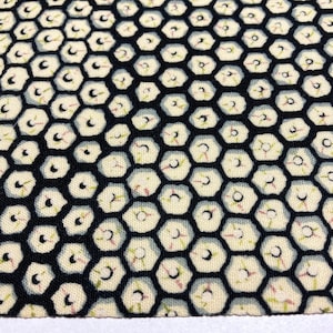 Puede incluir: Una tela negra con un patrón repetitivo de formas hexagonales blancas. Las formas tienen un contorno azul claro y un pequeño diseño rojo y verde en el interior.