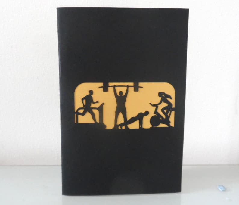 Peut inclure: Carte de v&oelig;ux noire avec un motif d&eacute;coup&eacute; repr&eacute;sentant des silhouettes de personnes faisant de l'exercice. Le motif comprend une personne courant sur un tapis roulant, soulevant des poids, faisant des pompes et faisant du v&eacute;lo. Le fond est jaune.