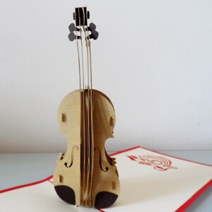 May include: A brown wooden pop-up card of a violin. The violin is intricately detailed and has a realistic appearance.