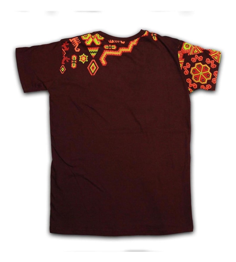 Pu&ograve; includere: Una t-shirt marrone scuro con intricati ricami geometrici nei toni dell'arancione, giallo e rosso. Il design &egrave; concentrato sulle spalle e sulla manica, creando un contrasto visivo sorprendente con il tessuto tinta unita.